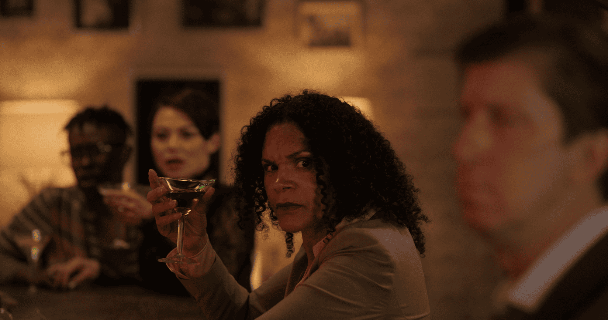 A picture of people in a bar with a black woman as center front sitting at bar.