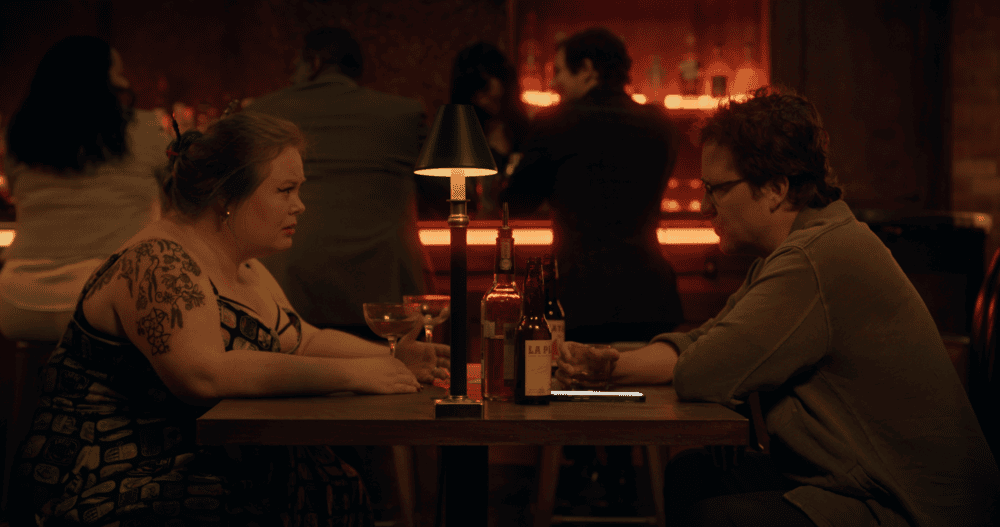 A woman and man sitting at a bar with drinks in their hands.