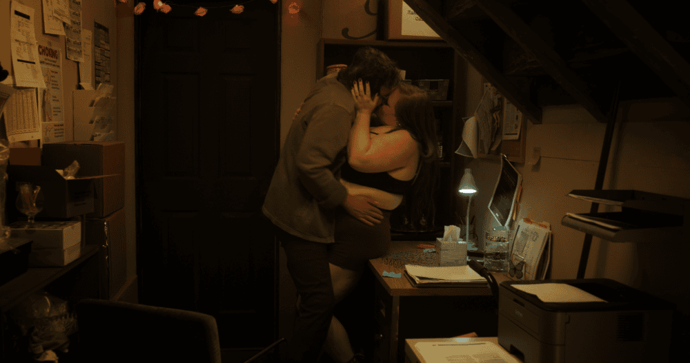 A man and woman kissing in a room very passionately.