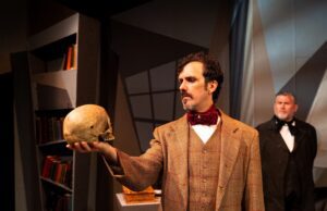 Michael Mullen makes Poe’s first detective impossible to ignore in Theatre 40’s The Case-Book of C. Auguste Dupin Michael Mullen as C. Auguste Dupin examines a skull as Todd Andrew Ball looks on in Theatre 40’s The Case-Book of C. Auguste Dupin. Photo by Eric Keitel.